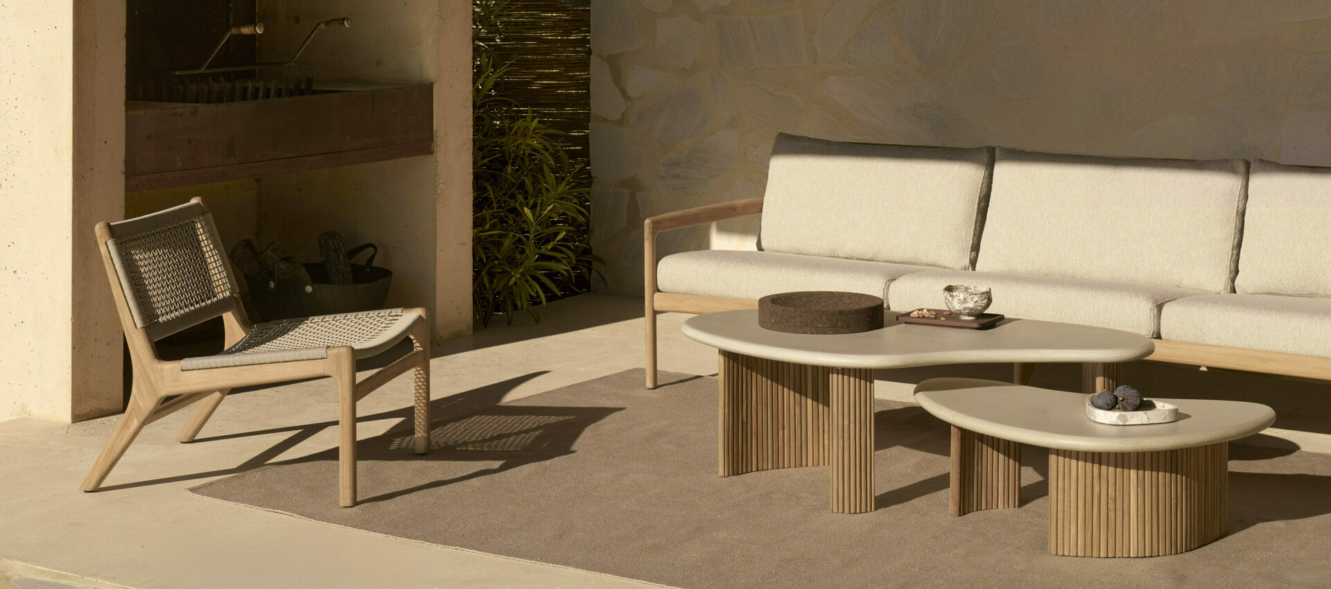 Ensemble de mobilier de jardin Ethnicraft avec fauteuil Jack Woven, canapé 3 places Jack, table basse Boomerang et tapis Nomad, disponibles chez Mise en Scène